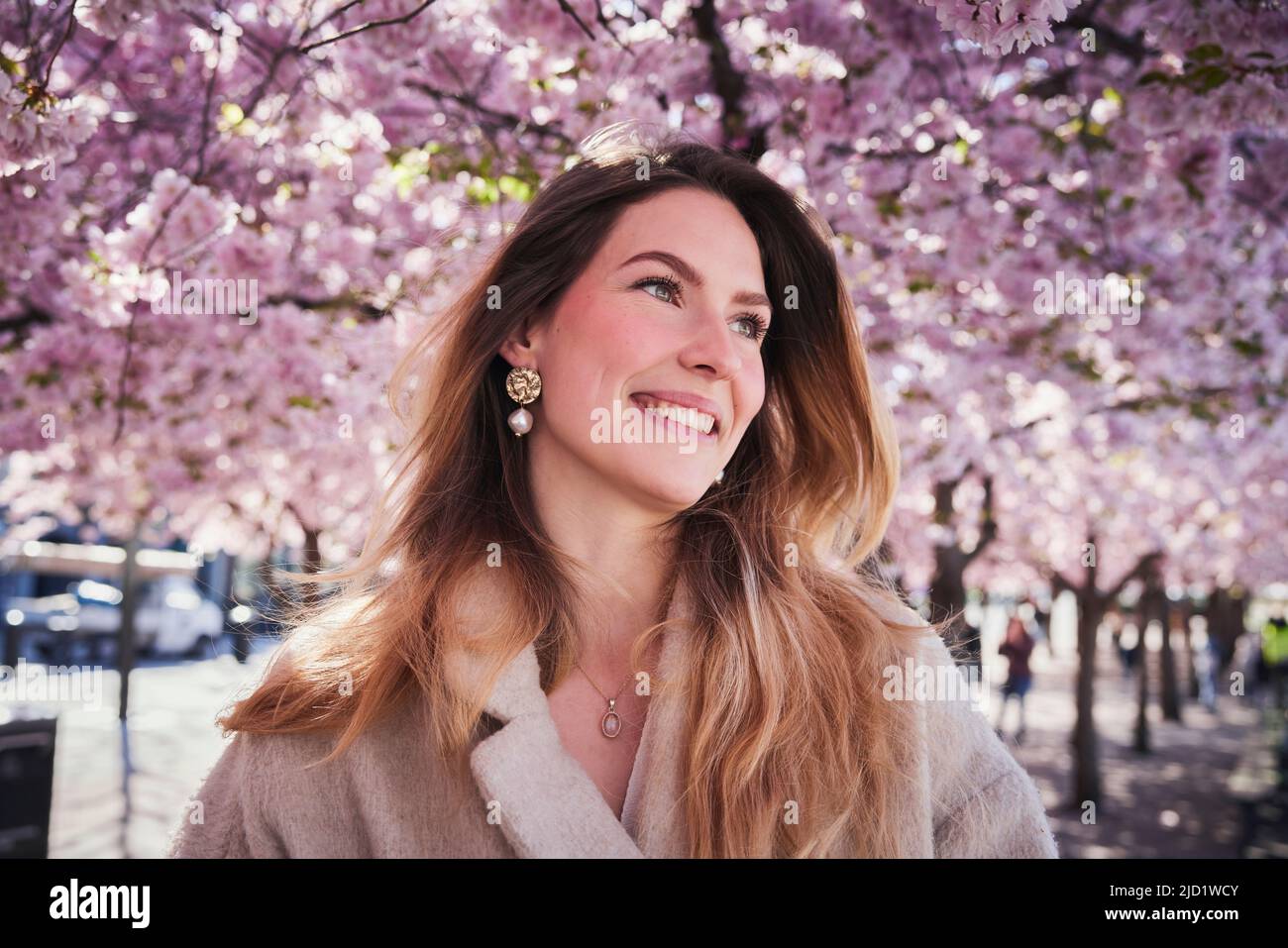 Young woman standing under cherry blossom Stock Photo - Alamy