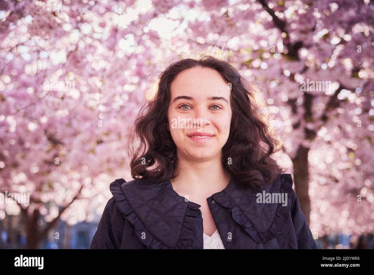 Portrait of young woman standing under cherry blossom Stock Photo - Alamy