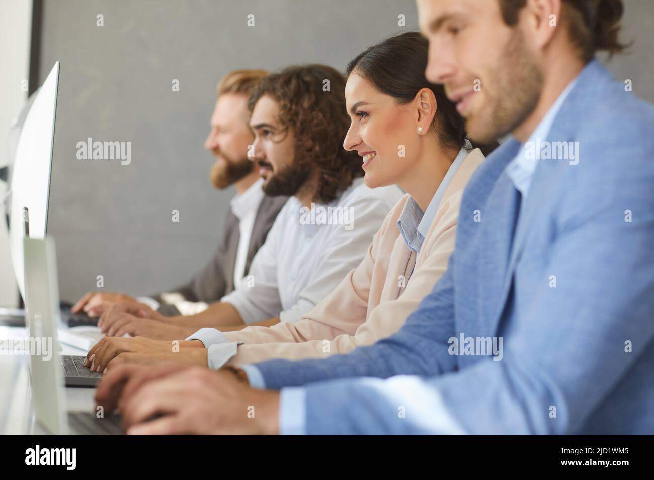 Side view of group of business people sitting at office desk and working on computers Stock Photo