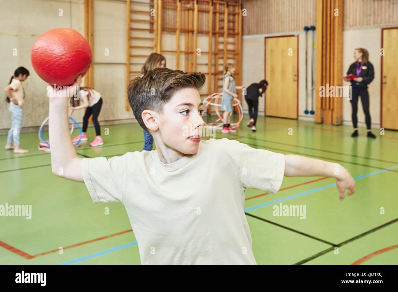 Boy throwing ball during PE class in school gym Stock Photo Alamy