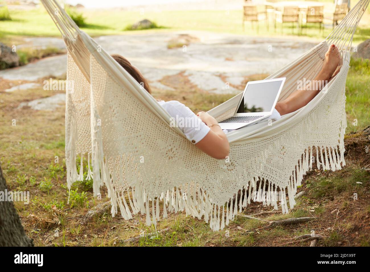 Woman using laptop in hammock Stock Photo