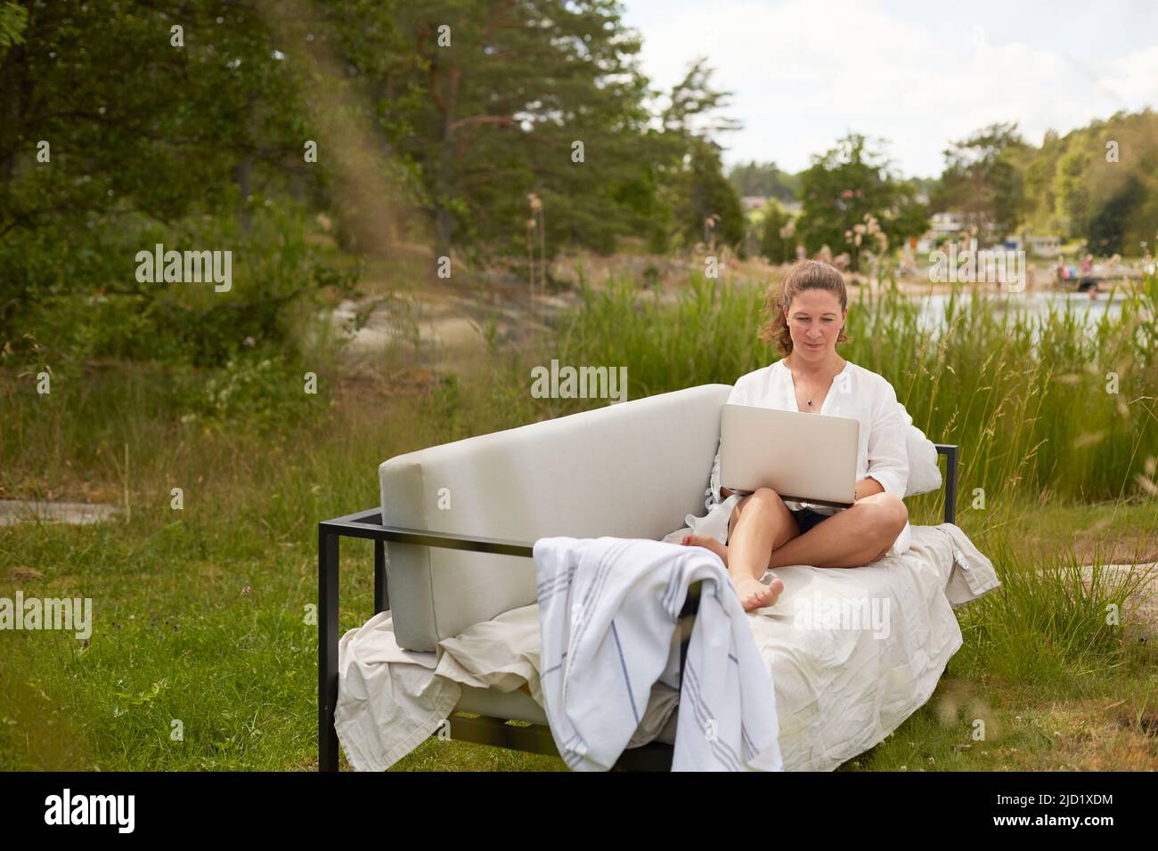 Woman using laptop on garden bench Stock Photo