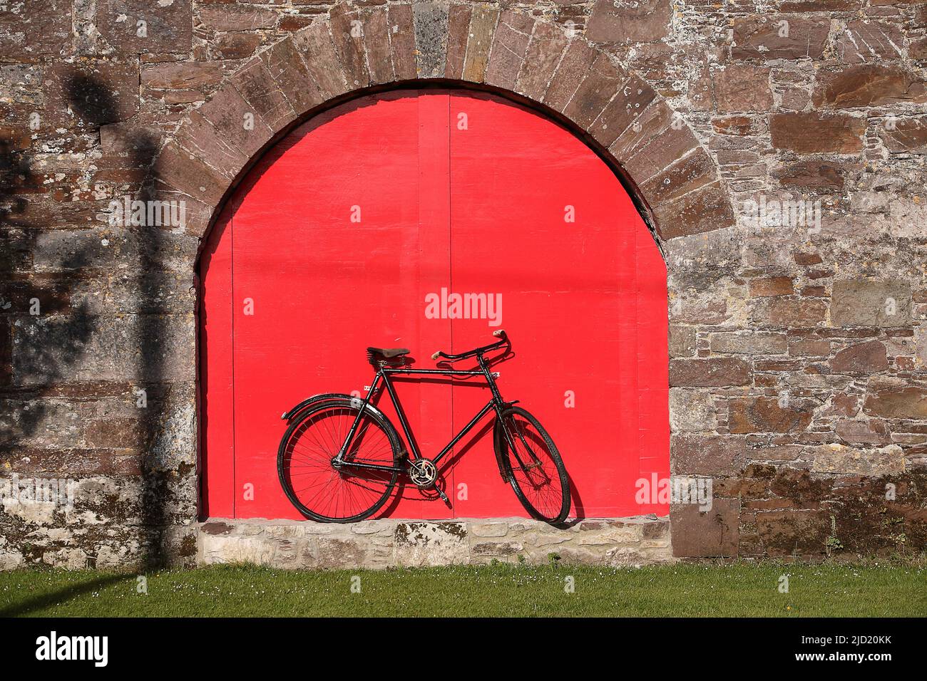 Old bicycle against red door Stock Photo