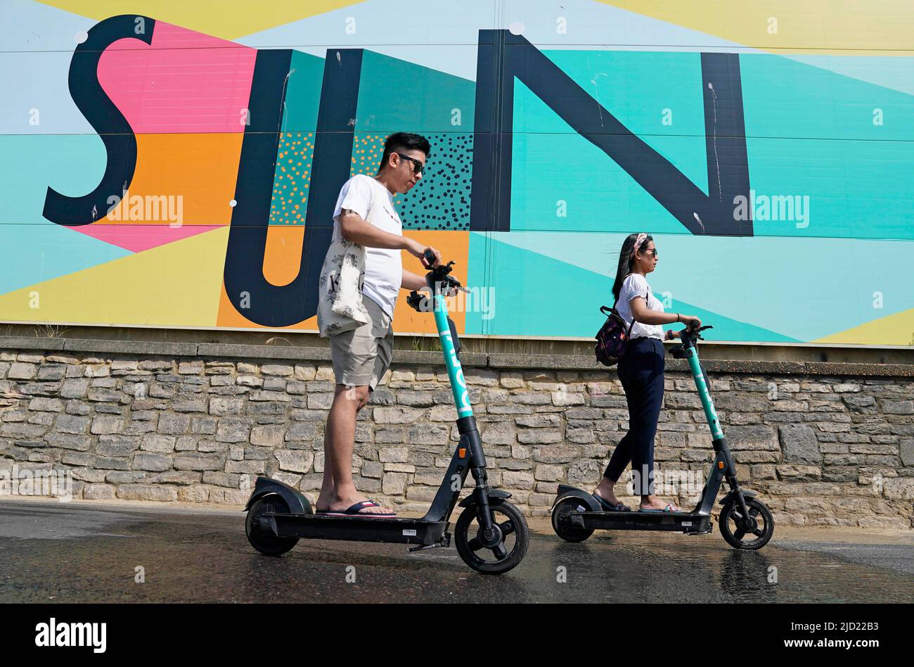 People scooter past a sign at Boscombe Beach in Dorset. A sweltering 34C  (93.2F) is expected in London and potentially some spots in East Anglia on  Friday, according to the Met Office.