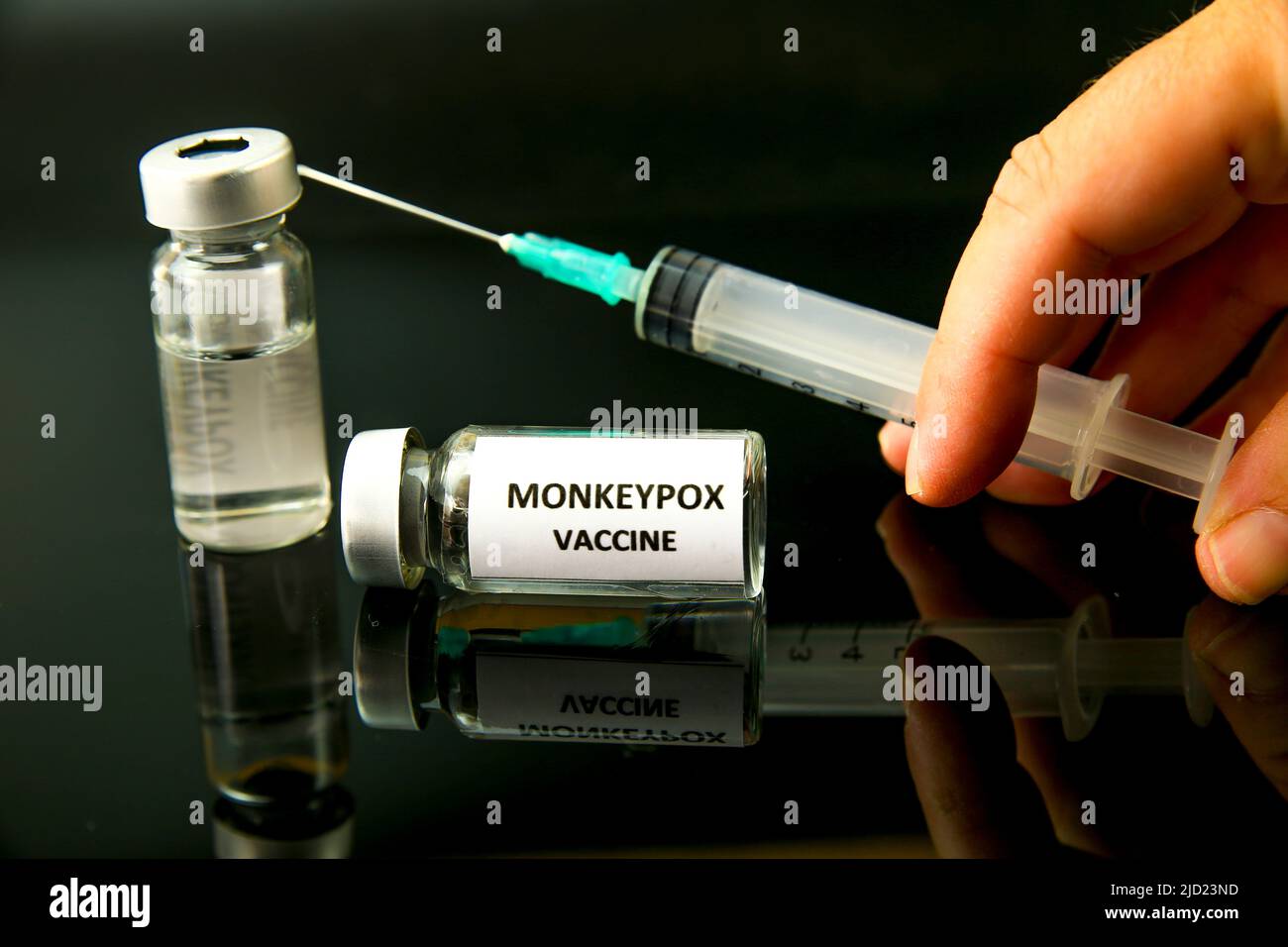Hand holding a syringe filled with Monkeypox vaccine on black ...