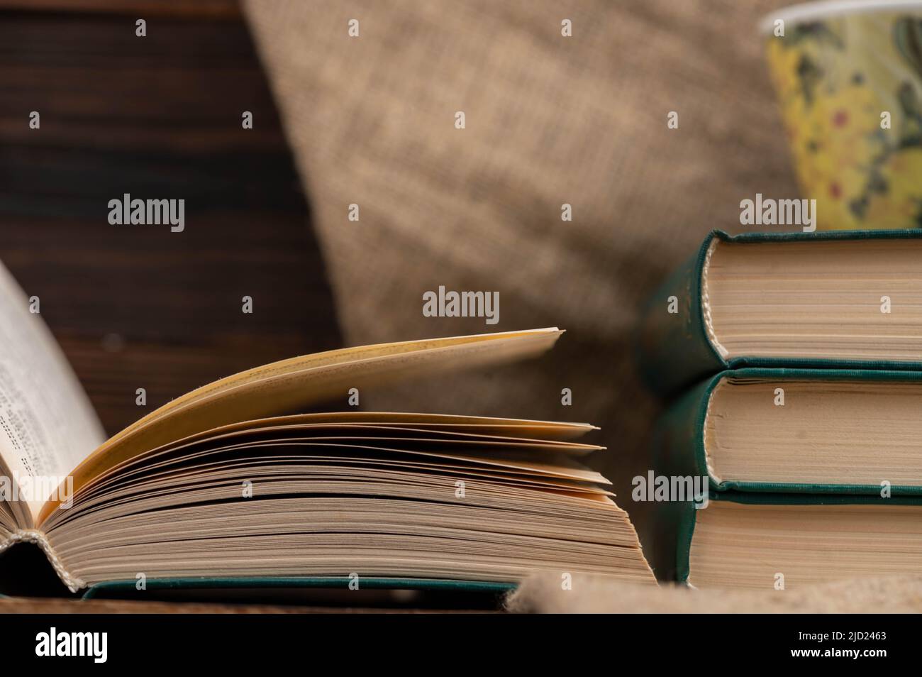 A cup of strong tea on a saucer and a stack of books on the table. Stock Photo