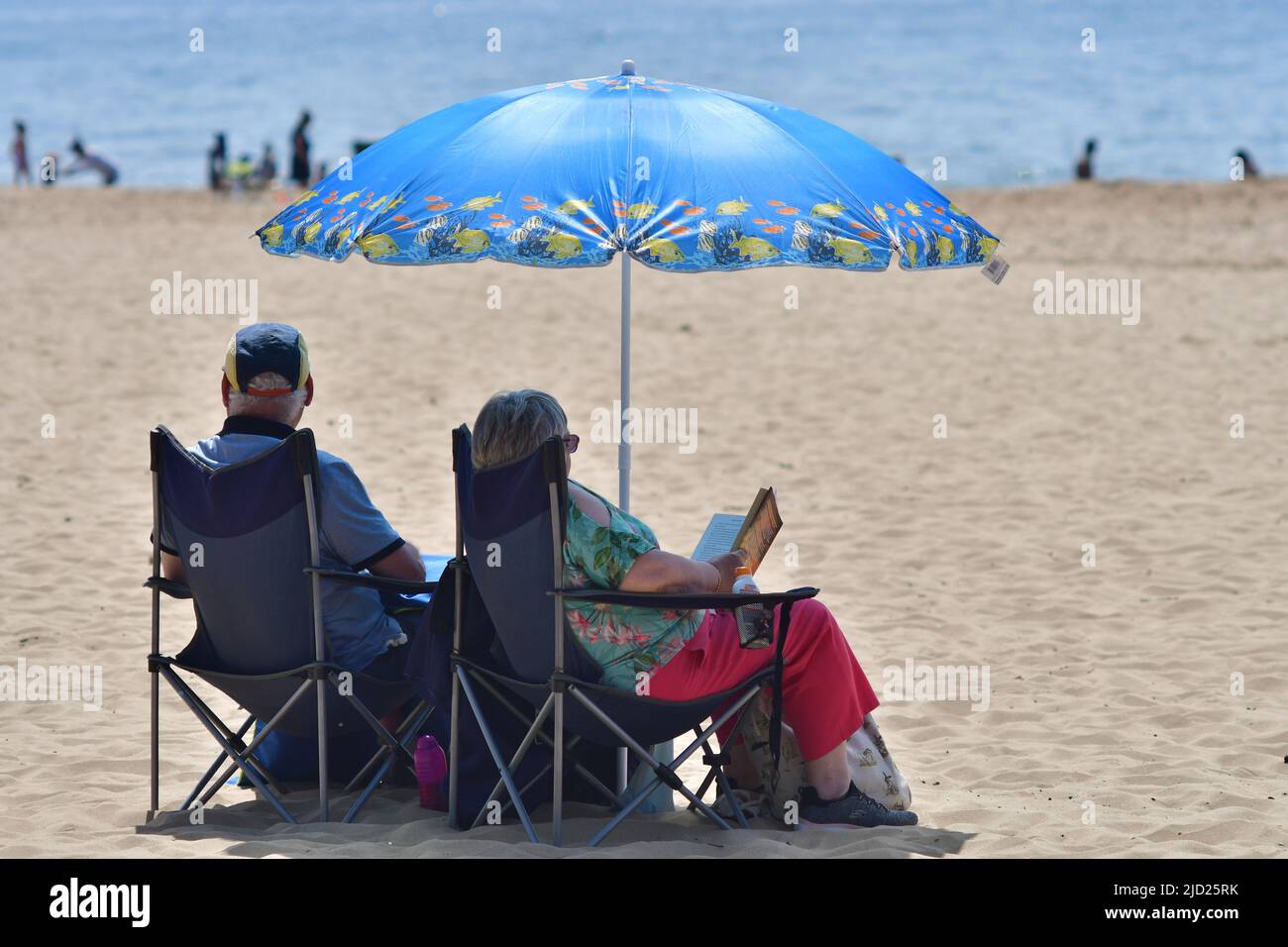 Boscombe, Bournemouth, Dorset, UK. 17th June, 2022. Weather. Set to be the hottest day of the year so far as the short heatwave peaks. Senior couple sitting on the beach in chairs in shade under a beach umbrella. Credit: Paul Biggins/Alamy Live News Stock Photo