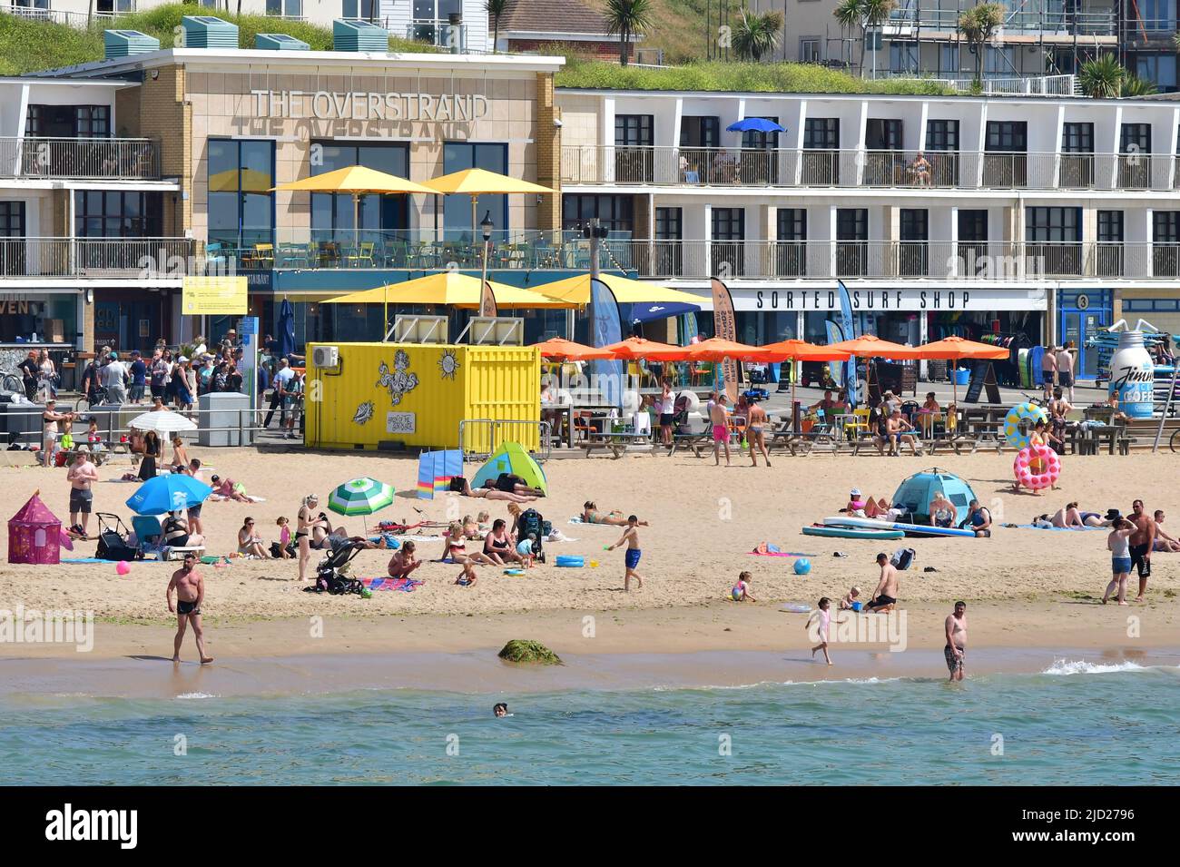 Boscombe, Bournemouth, Dorset, UK, 17th June 2022, Weather. Set to be the hottest day of the year so far as the short heatwave peaks. People head to the beach for the sunshine and some fresher sea air in front of The Overstrand restaurant and surf shop. Credit: Paul Biggins/Alamy Live News Stock Photo