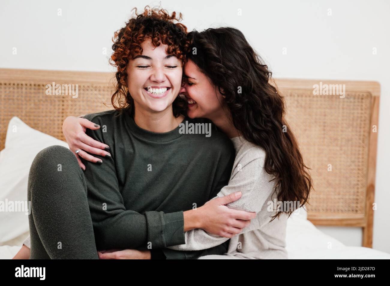 Gay female couple surprising lover with engagement ring in bed at home - Lgbt lesbian love and romance concept Stock Photo