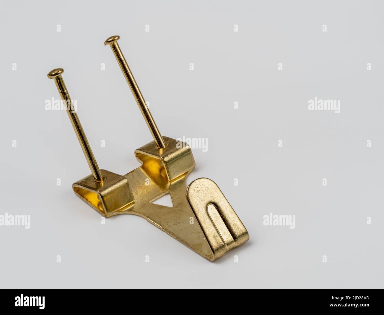 close up flat lay image of a double fixing single hook brass  metal wall mounted picture hook Stock Photo