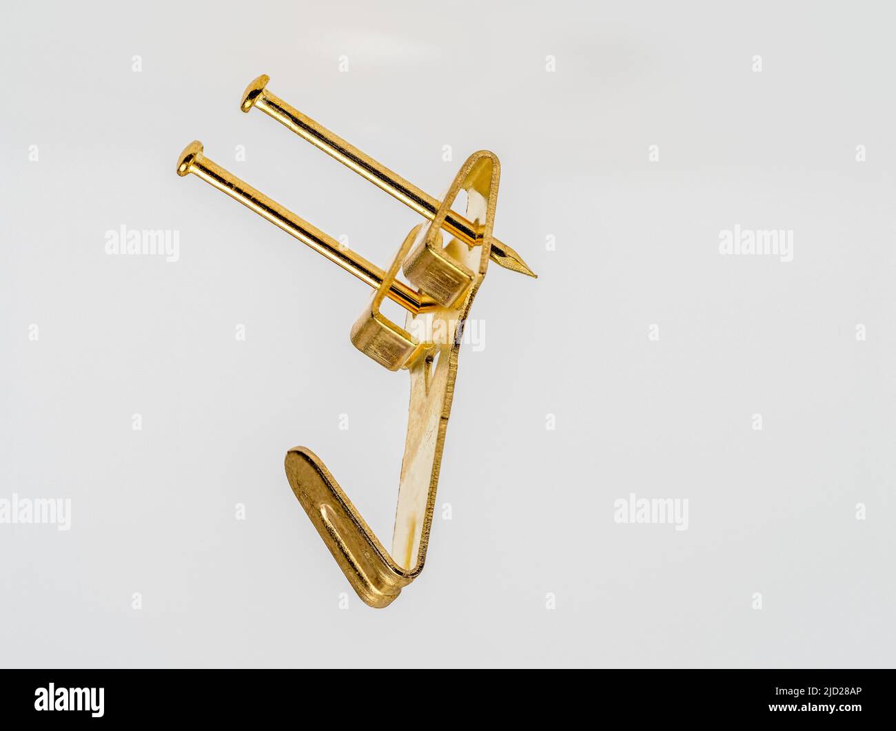 close up floating image of a double fixing single hook brass  metal wall mounted picture hook Stock Photo