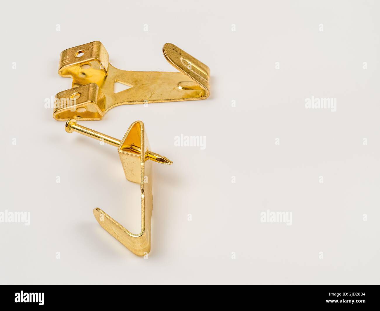 close up flat lay image of a pair of single hook brass  metal wall mounted picture hooks Stock Photo