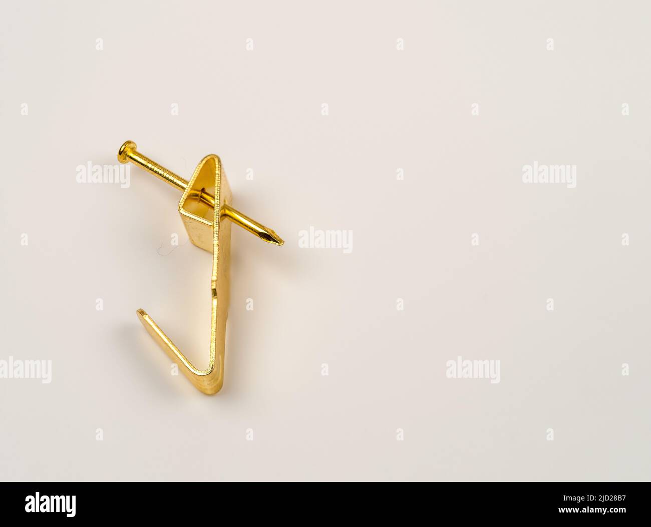 close up flat lay image of a single fixing single hook brass  metal wall mounted picture hook Stock Photo