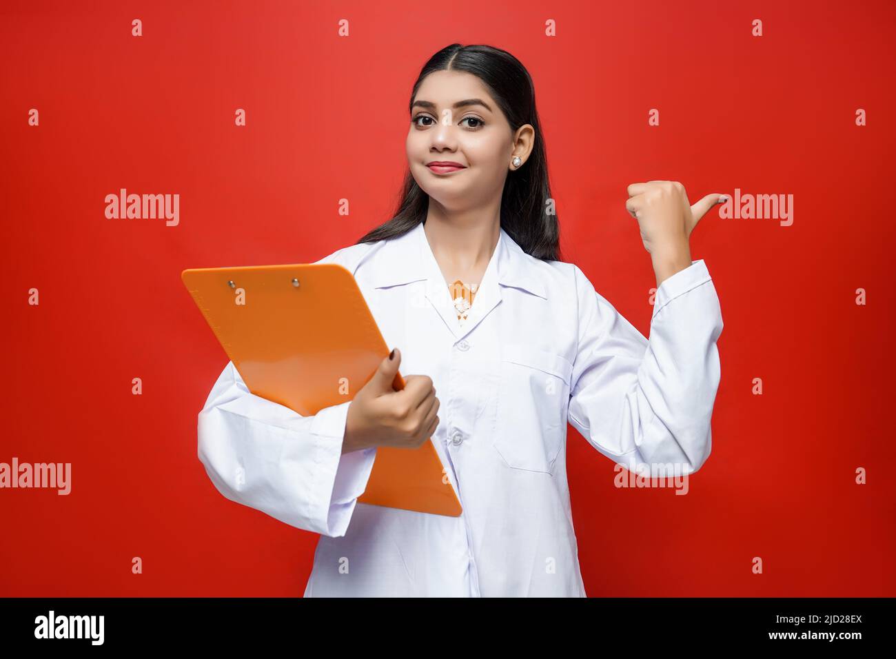 Female doctor standing with writing pad and doing actions with hand showing direction Stock Photo