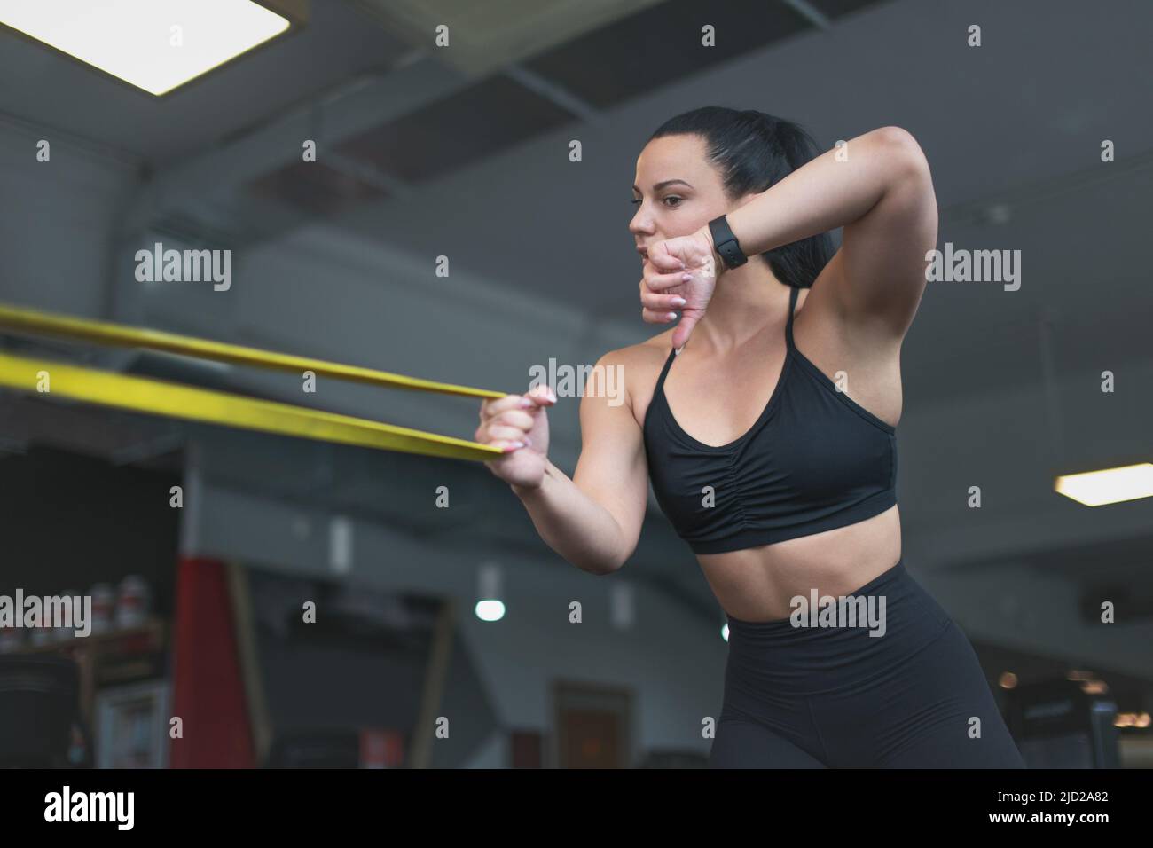 Young sporty Caucasian woman calling by smartwatch during workout by rubber band Stock Photo