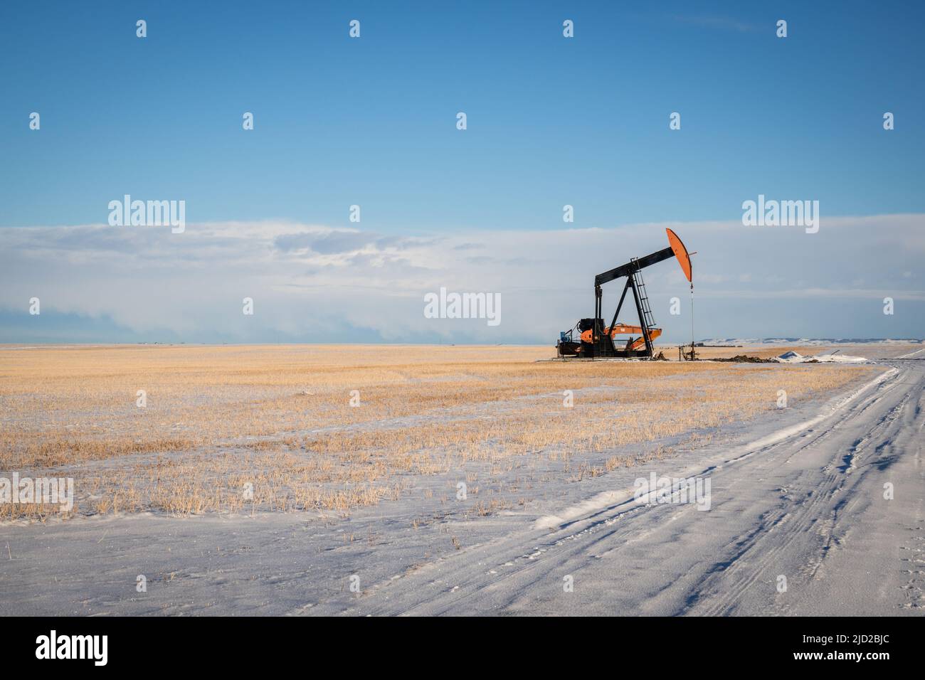 Small oil pump in field covered in snow with copy space. Stock Photo