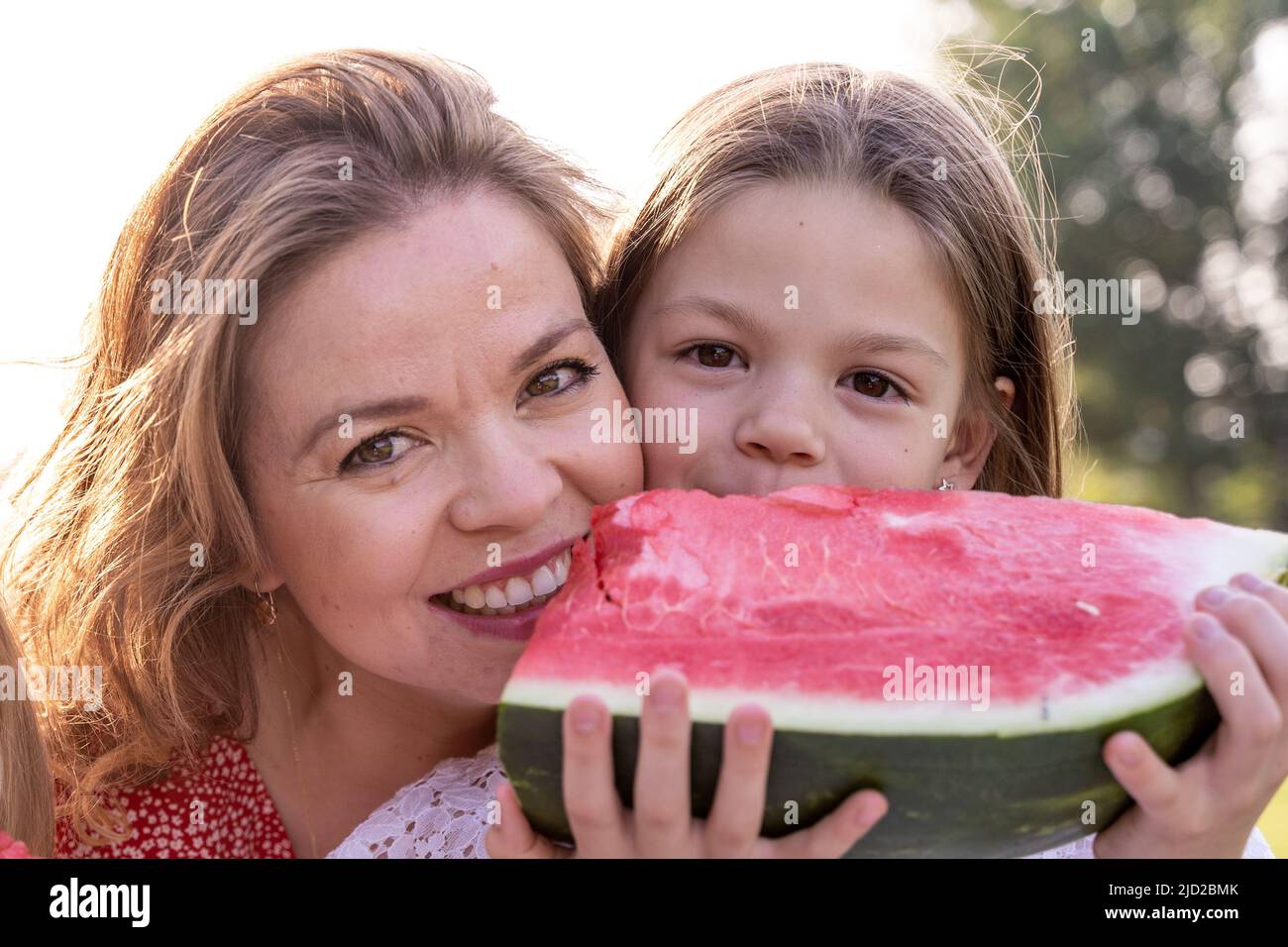 portrait of mom with cute daughters have fun while eating a slice of ...