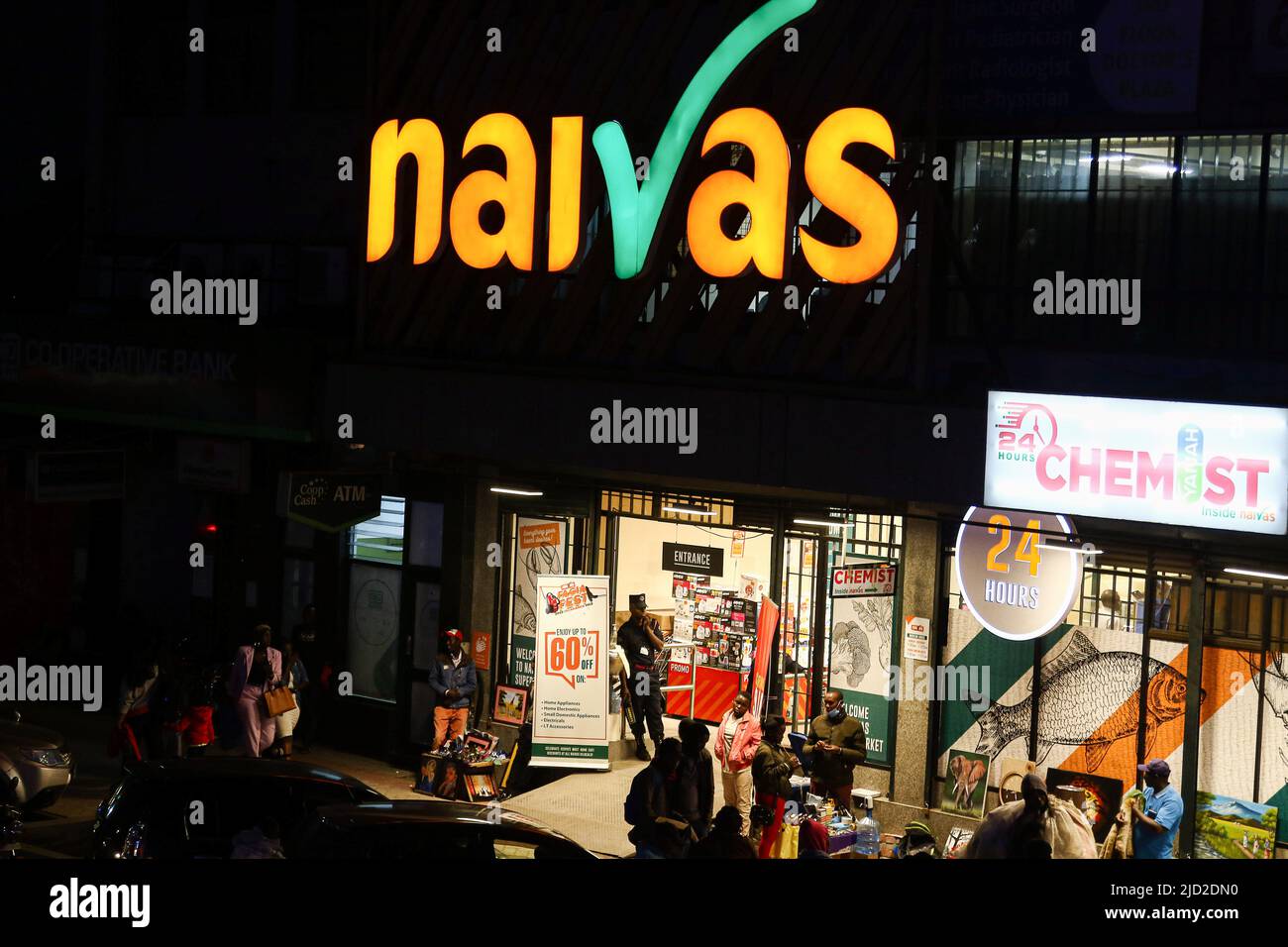 People are seen walking past a branch of Naivas Supermarket, one of