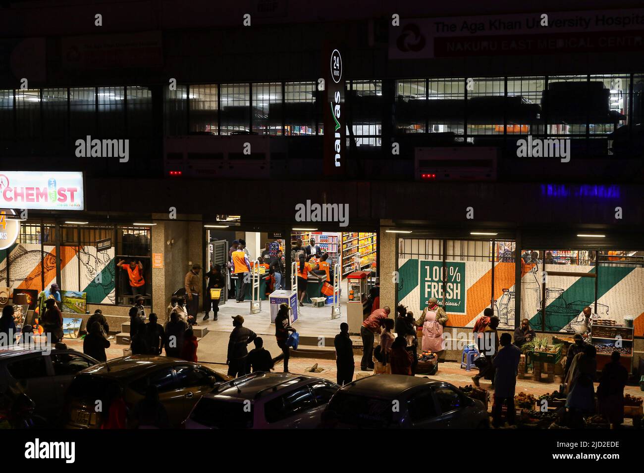 People are seen walking past a branch of Naivas Supermarket, one of