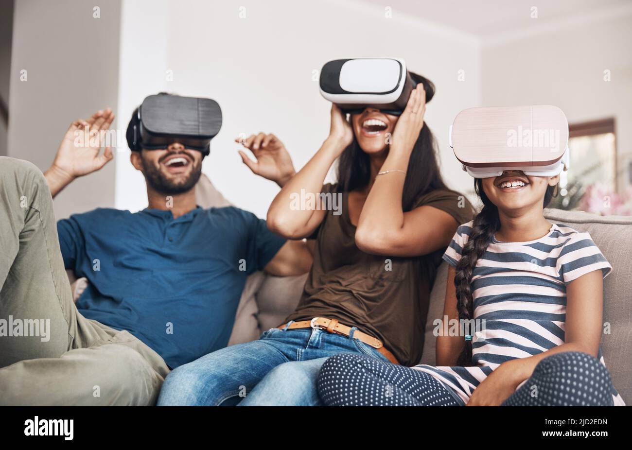 The future of family entertainment is here. Shot of a young family using virtual reality headsets together at home. Stock Photo
