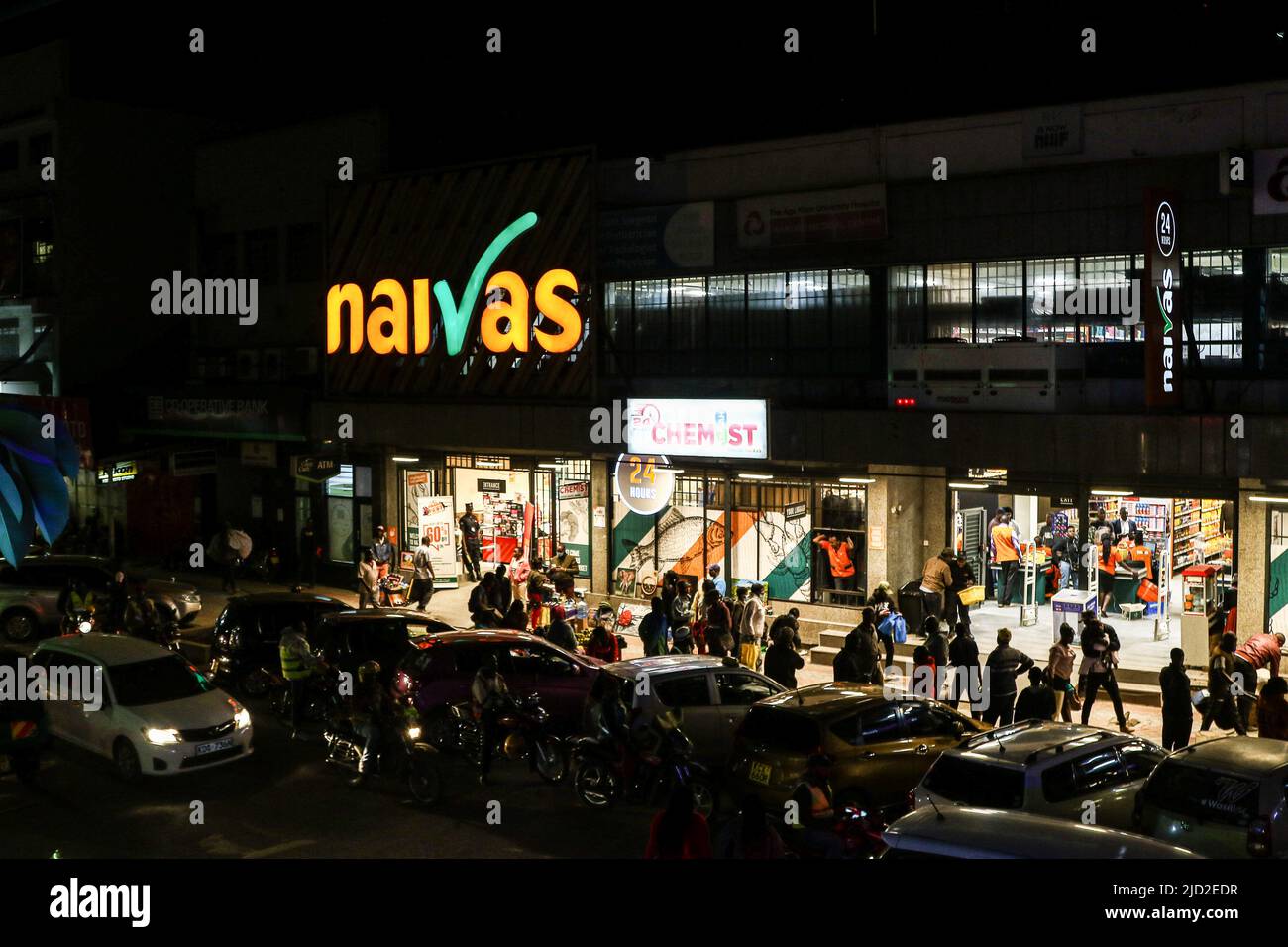 People are seen walking past a branch of Naivas Supermarket, one of