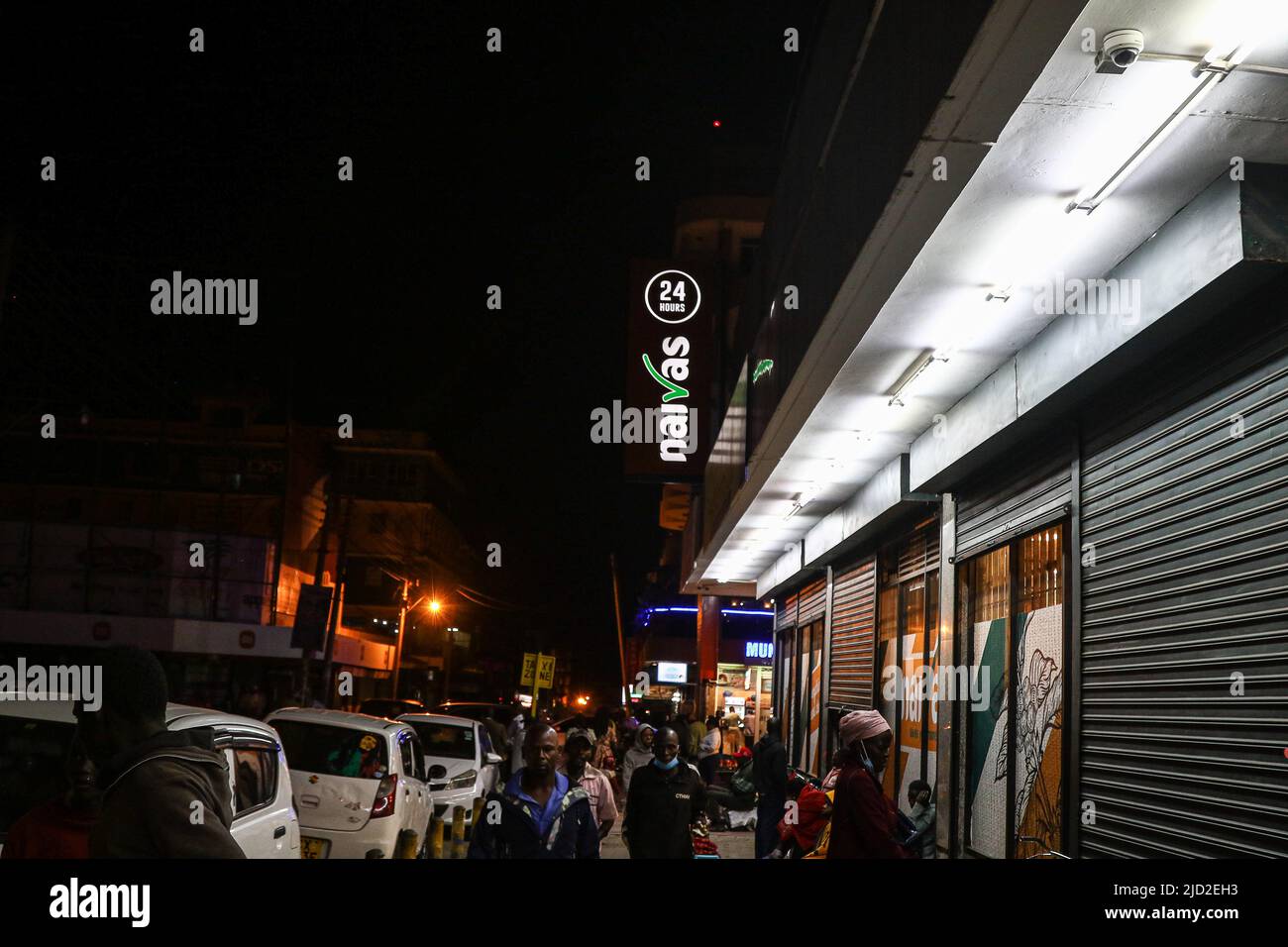 People are seen walking past a branch of Naivas Supermarket, one of