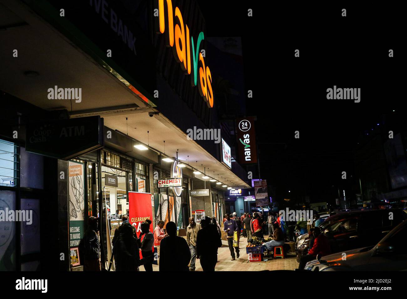 People are seen walking past a branch of Naivas Supermarket, one of