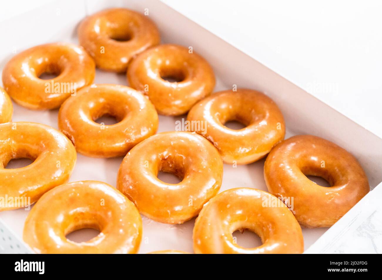 Plain glazed storebought doughnuts in a white paper box Stock Photo
