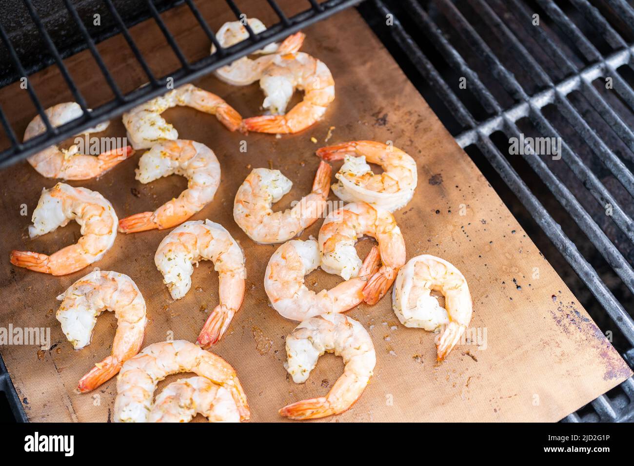 Grilling shrimp on a grill mat over an outdoor gas grill Stock Photo