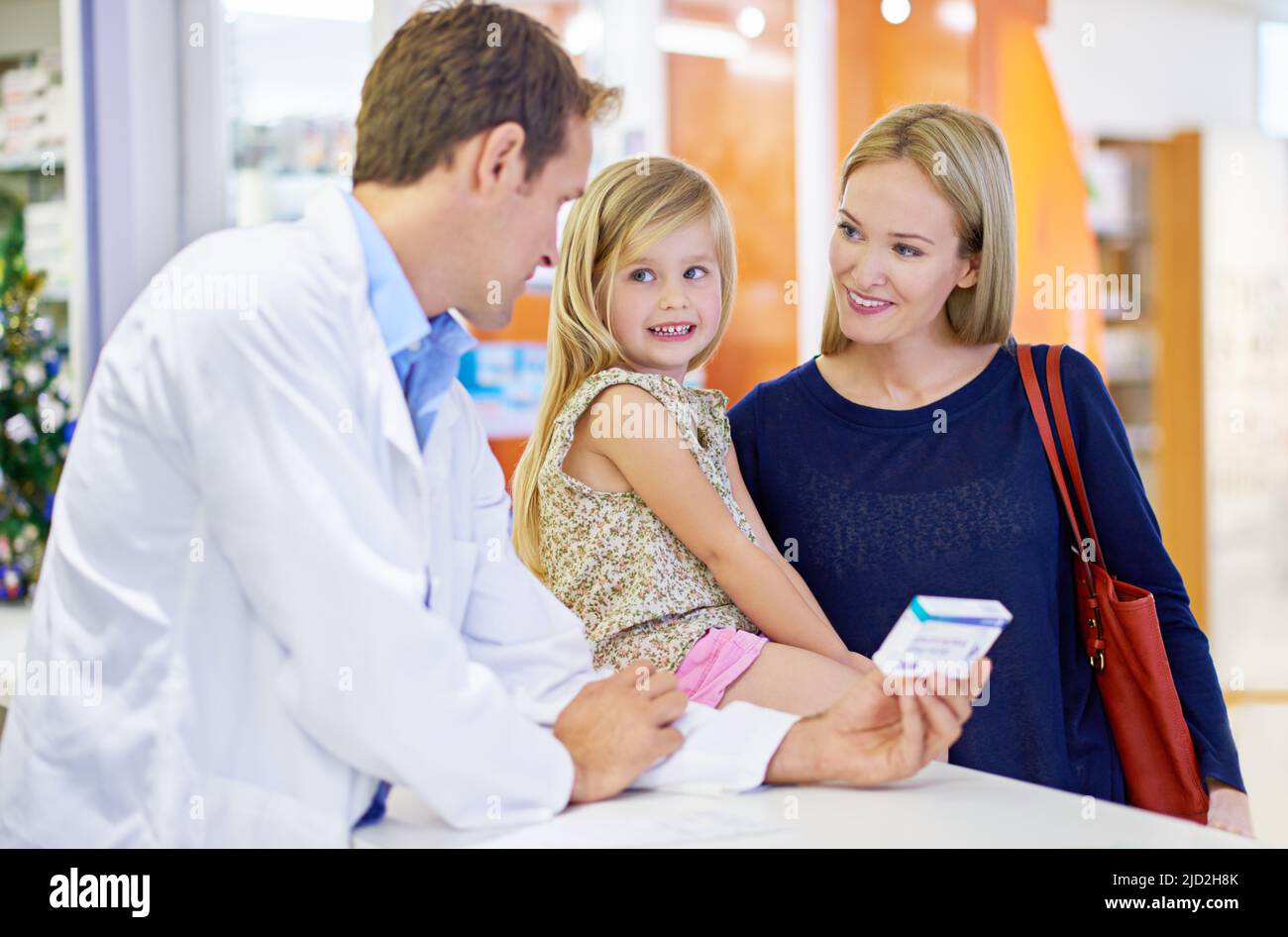 Are you ready to feel better. A pharmacist giving medication to a mother and daughter. Stock Photo