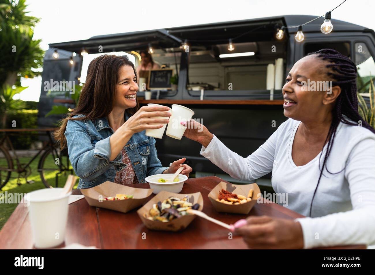 Happy multiracial senior friends having fun eating in a street food truck market Stock Photo