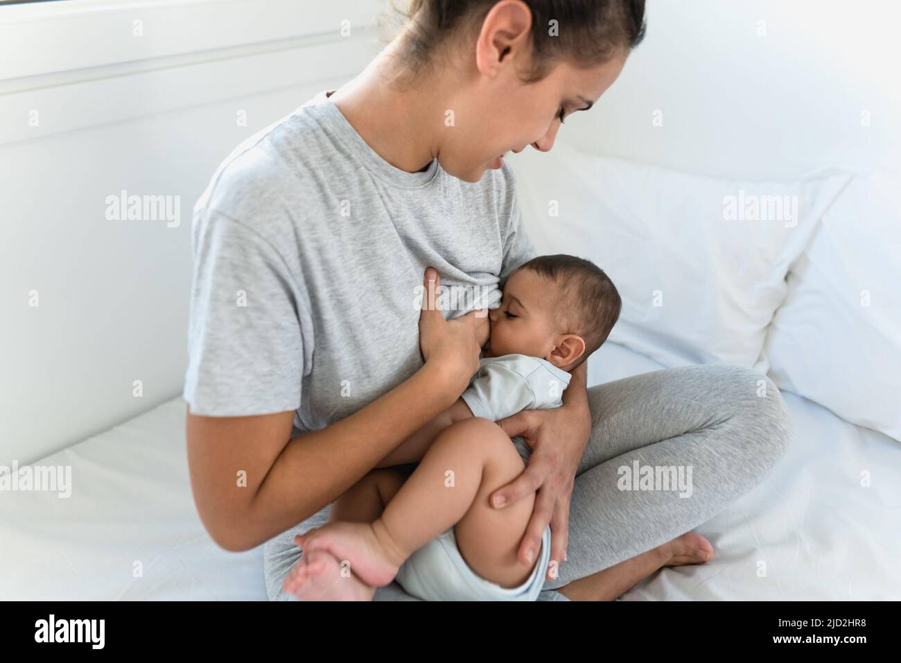 Happy mother breastfeeding her little baby on bed - Family and Maternity concept Stock Photo