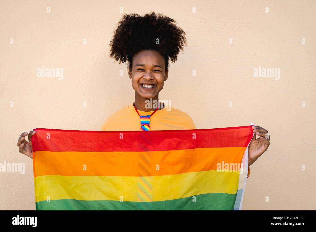 Happy African gay woman celebrating pride holding rainbow flag outdoor - LGBT concept Stock Photo