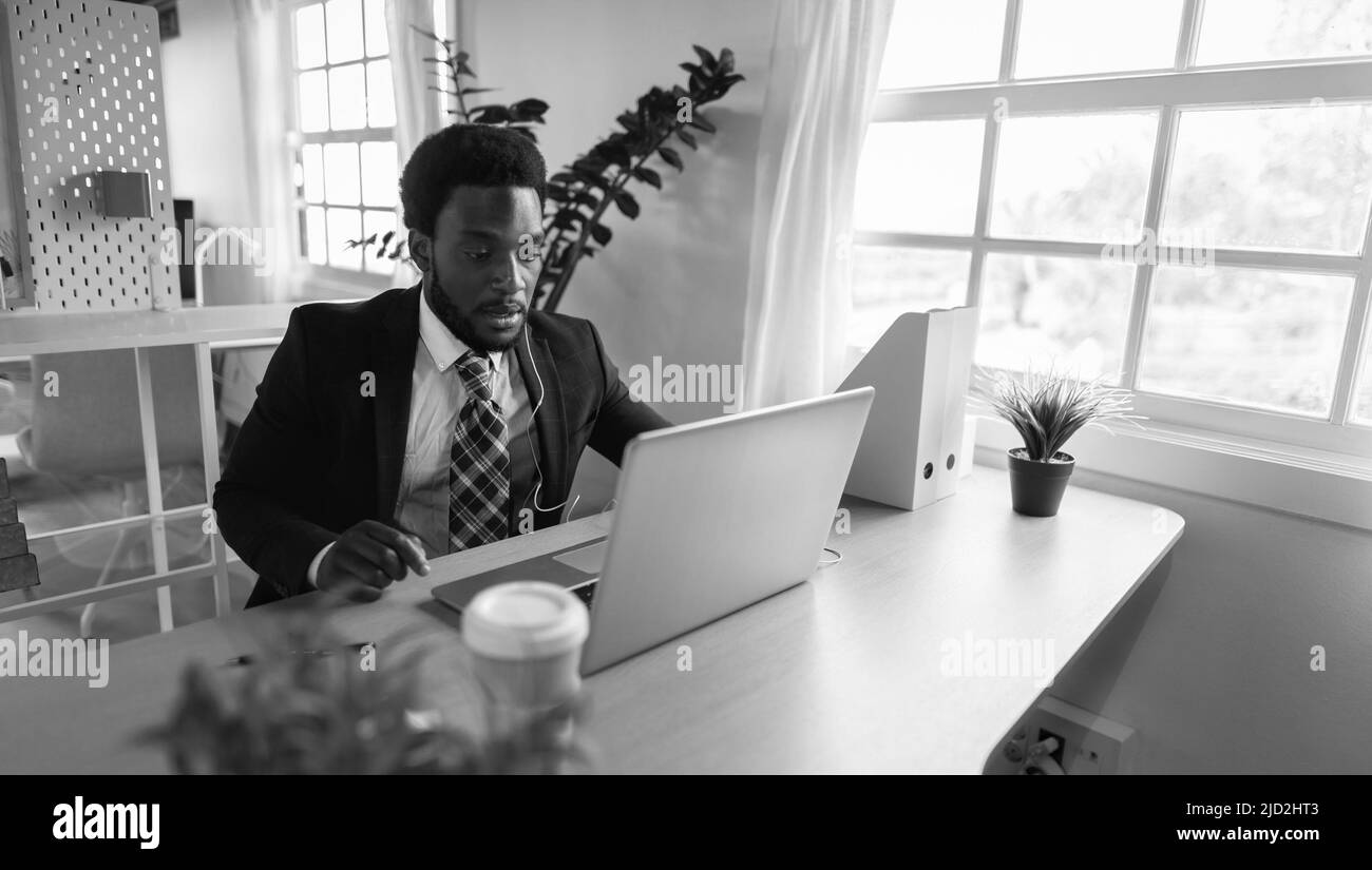 Business African man doing online video conference on laptop inside modern office - Black and white editing Stock Photo