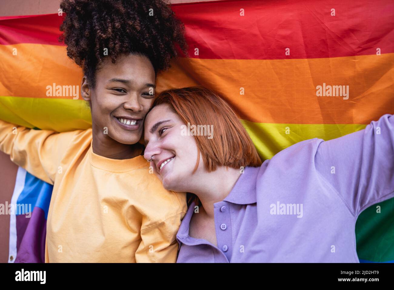 Happy gay couple celebrating pride holding rainbow flag outdoor - LGBTQ and love concept Stock Photo