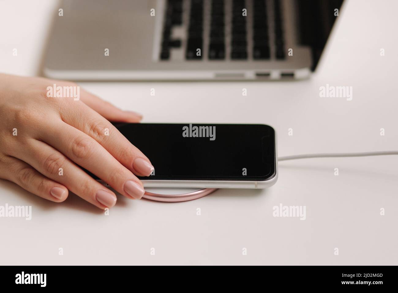 Female hand tup phone on wireless charging. Work place near at the