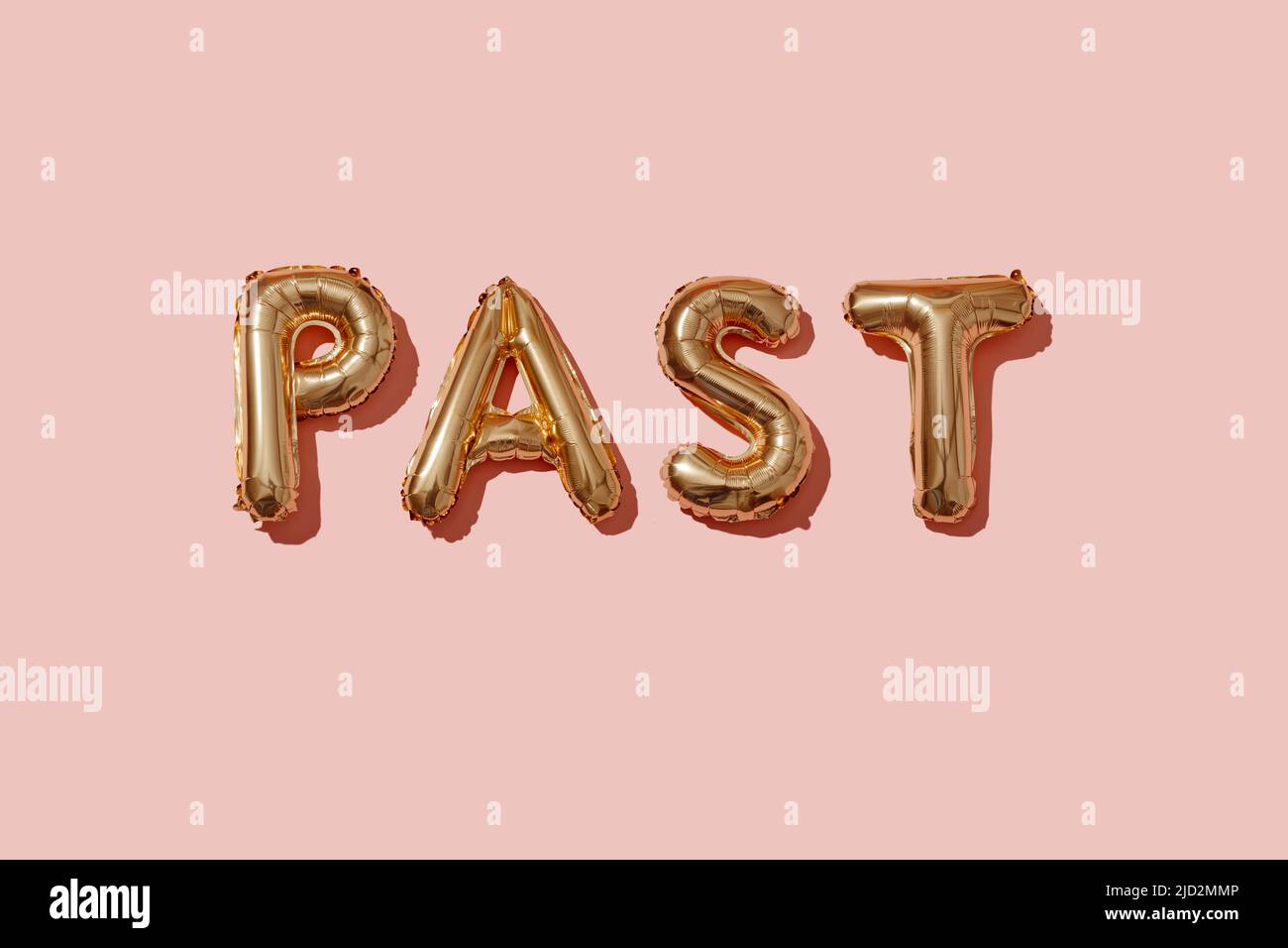 some golden letter-shaped balloons forming the word past on a pink background Stock Photo