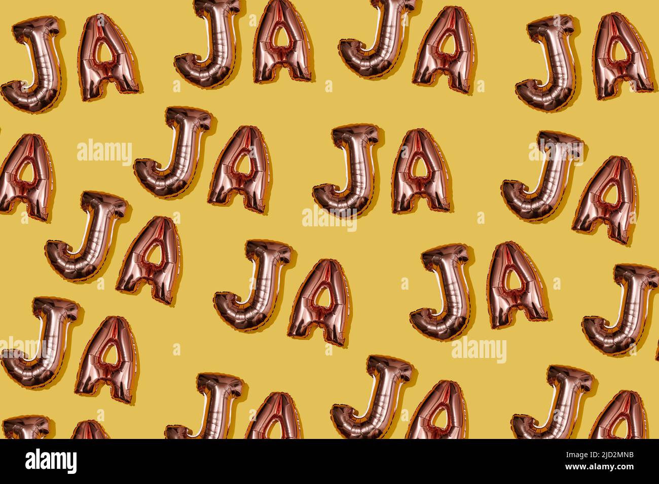 many metallic pink letter-shaped balloons forming the interjection ja ja ja, representation of laughter in spanish, repeatedly on a yellow background Stock Photo