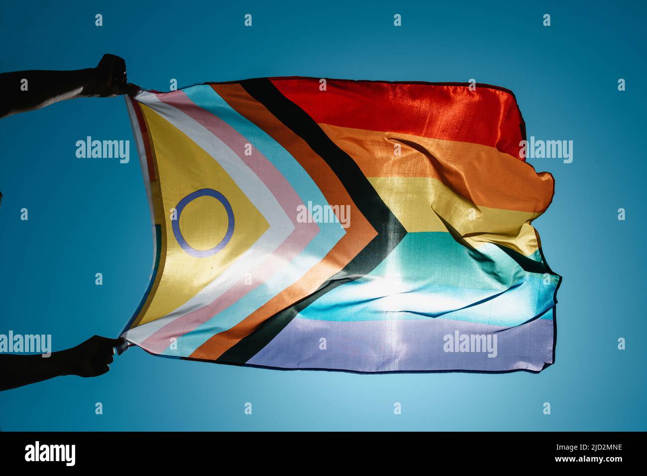 a man waves an intersex-inclusive progress pride flag in the wind on the sky Stock Photo