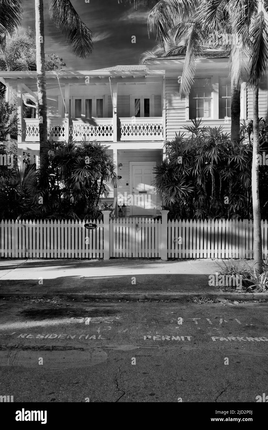 Beautiful Conch style home in the Old Town section in Key West, Florida, USA.  Surrounded with a white picket fence and palm trees.  Stark contrast. Stock Photo