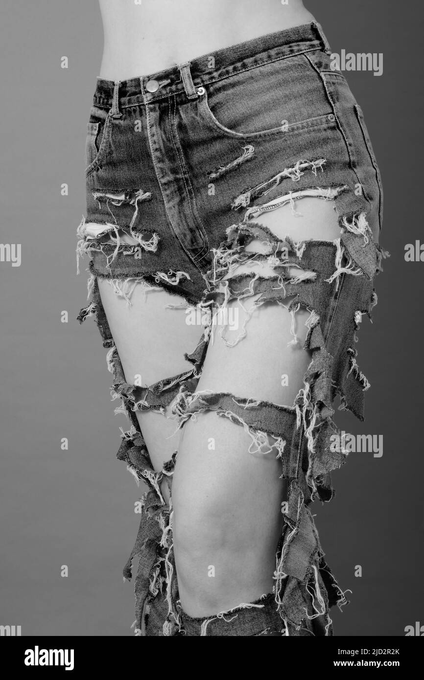 beautiful slim female legs in ripped jeans close up, monochrome Stock Photo