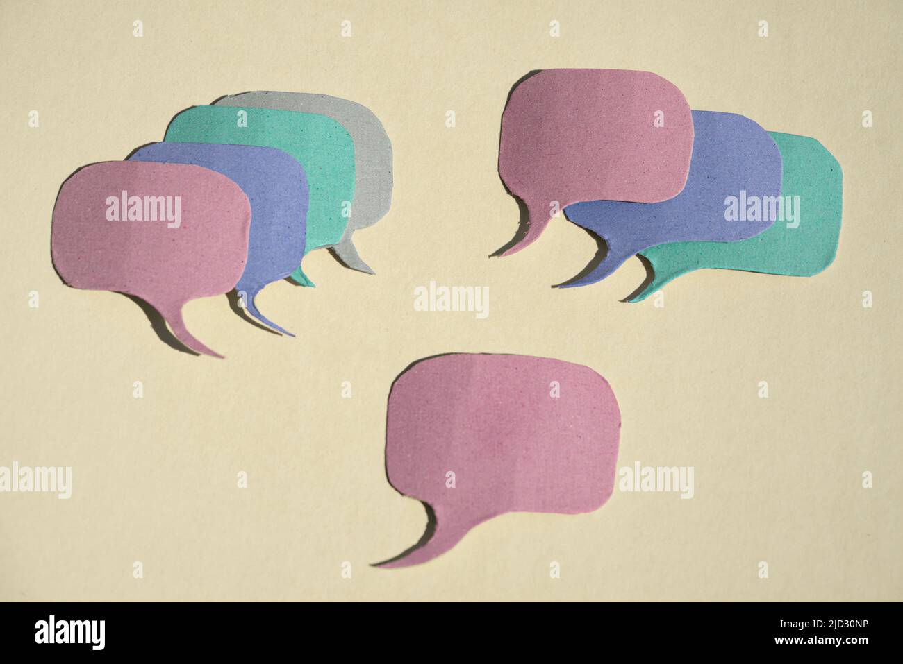 Pros and cons.Group of speech bubbles cut out of cardboard with multiple positions for and against the mainstream opinion. Stock Photo