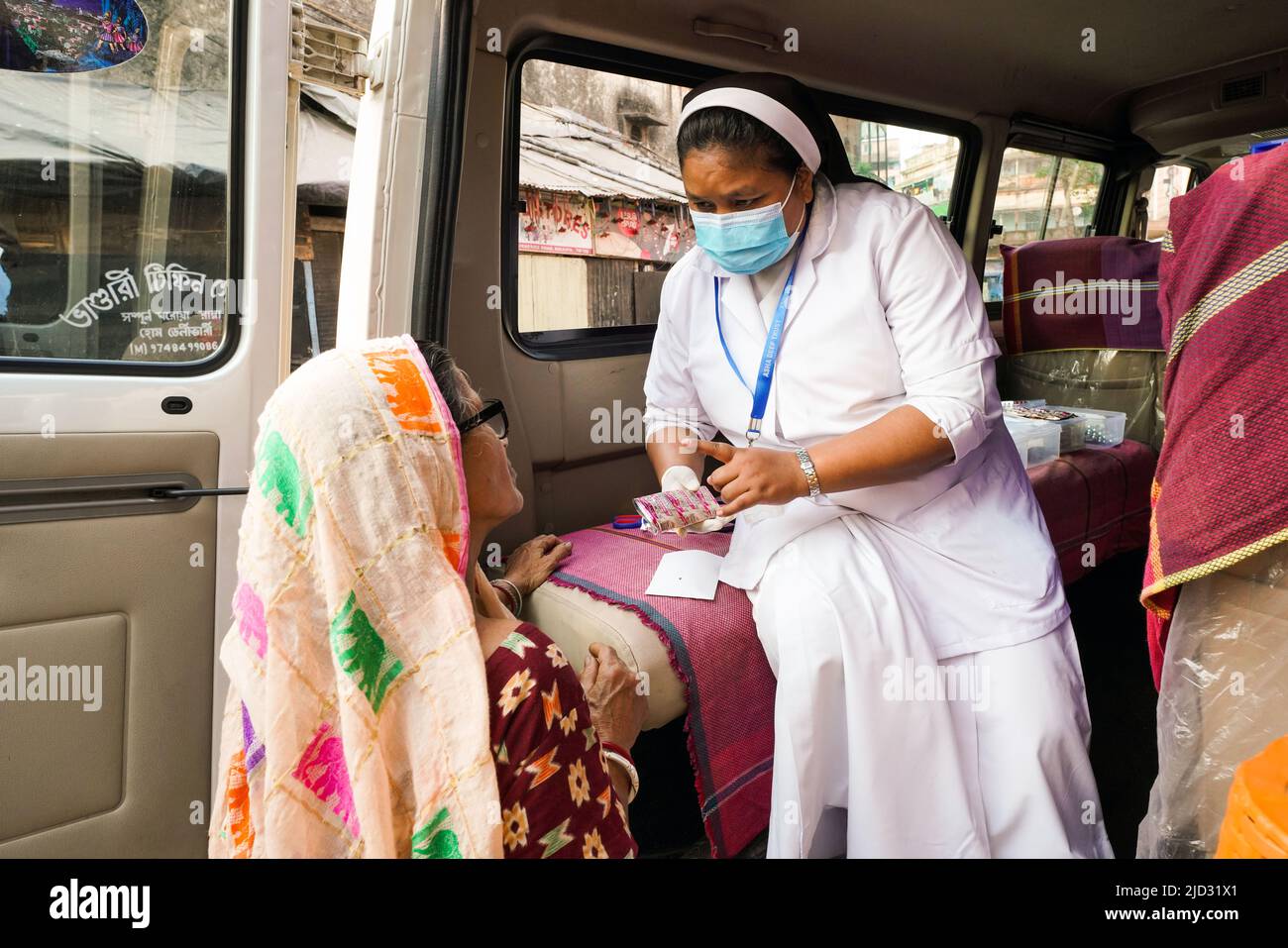 a Catholic sister counsels poor people from a slum on health issues at the Asha Deep Trust's Mobile Clinic in Kolkata, India Stock Photo