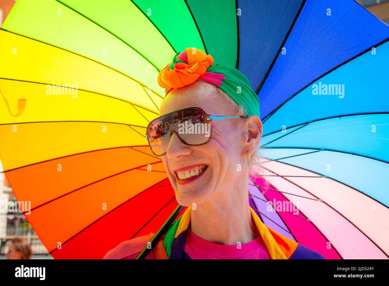 Transgender man or woman with a bright rainbow umbrella, UK 2022 Stock Photo