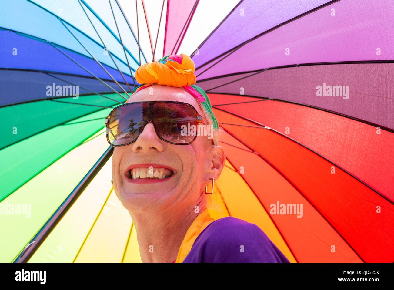Transgender man or woman with a bright rainbow umbrella, UK 2022 Stock Photo