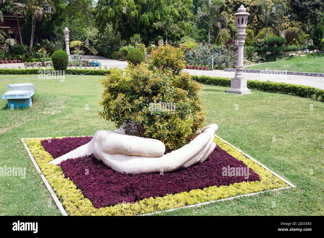 A large hand holds a bush in the Bishop's Garden of Varanasi, India Stock Photo