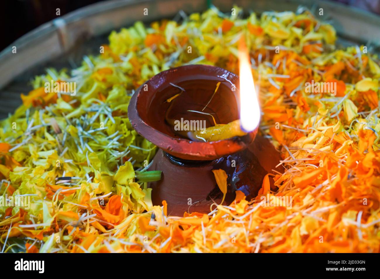 Flame in an oil lamp amidst a bowl of flowers, welcoming ceremony in an Indian ashram Stock Photo