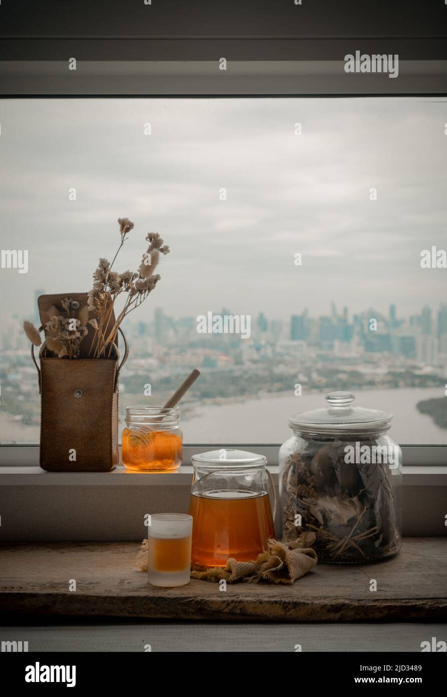 Refreshing with Chinese herbal tea (Jub Lieng) served with honey on old wooden table with city view. Herbal plant and healthy drinks concept, Selectiv Stock Photo