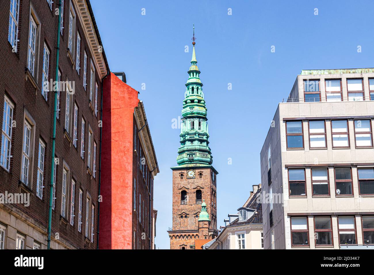 The old tower and spire of the Nikolaj Contemporary Art Center (Kunsthallen Nikolaj) seen through more modern buildings in Copenhagen, Denmark Stock Photo