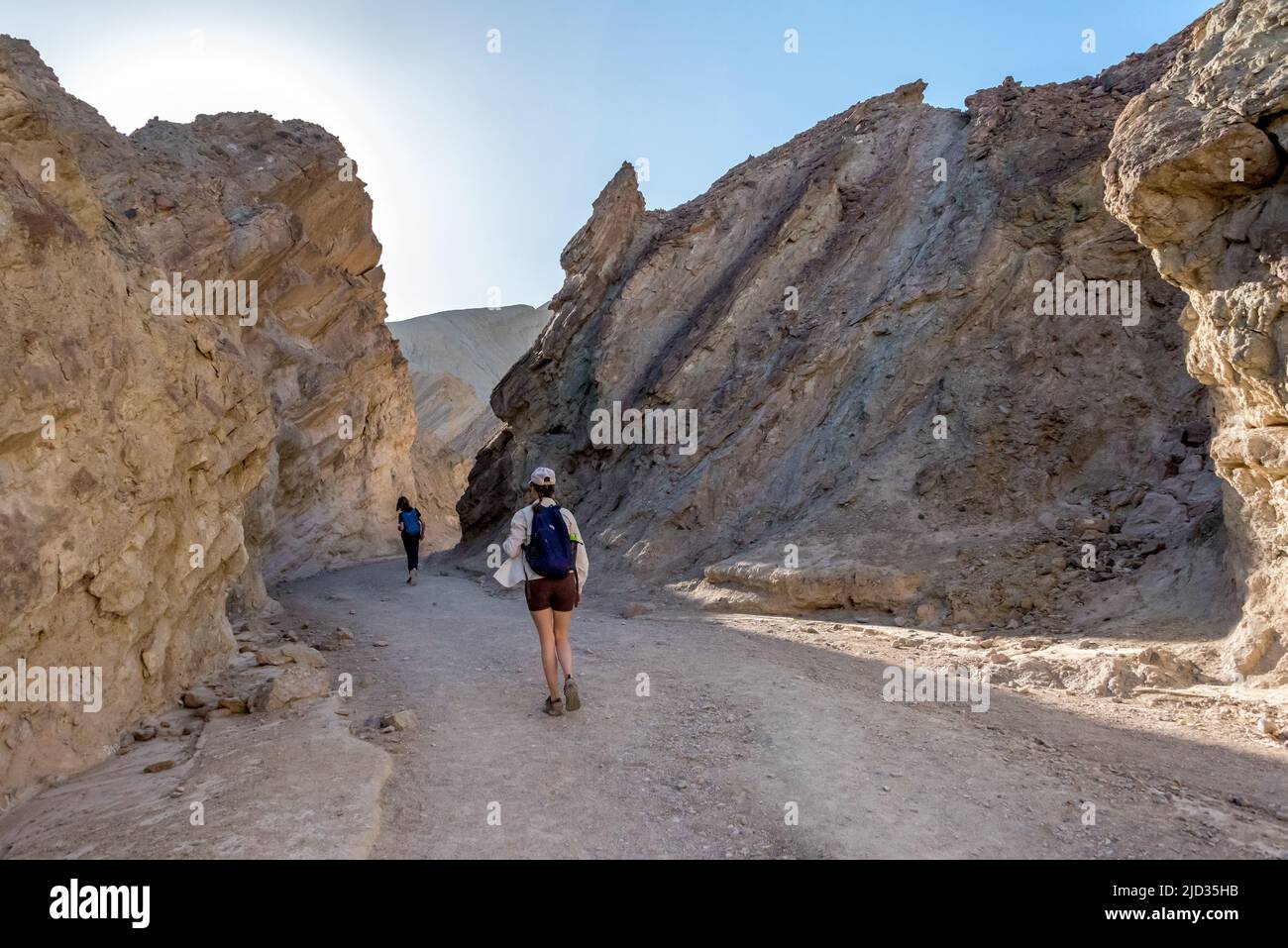 Hikers in Golden Canyon, walking between displaced sedimentary canyon walls in Death Valley National Park. Stock Photo